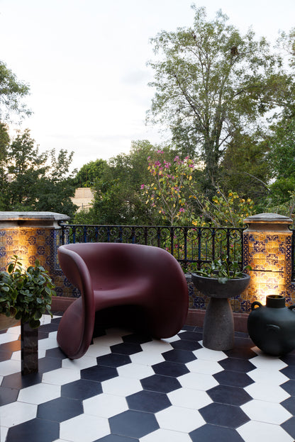 Fortune Chair by Heller in Dark Cherry on a modern patio in mexico with decorative tiles and plants.